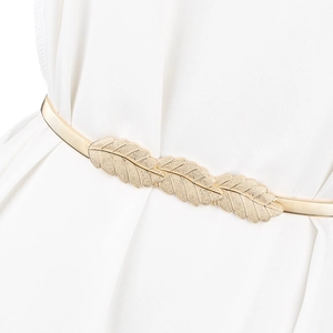 Detail of golden leaf metal buckle on elastic spring belt worn over a white dress