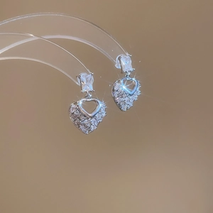 Detailed view of silver heart earrings with sparkling cubic zirconia on a display stand