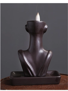 Macro detail of a ceramic female bust backflow incense burner with smoke on a woven mat