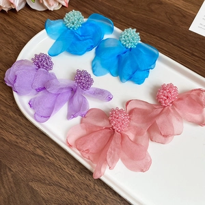 Detail of floral fabric earrings in blue, purple and pink on a ceramic tray