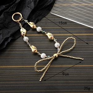 Golden irregular pearl and rhinestone bow phone charm lanyard with spring buckle