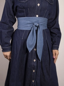 Detail showing the contrast light blue denim tie belt on a dark blue long sleeve dress