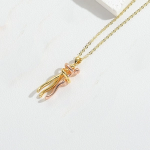 Close-up of a two-tone embrace pendant necklace in gold and rose gold on white leather