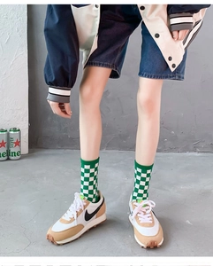 Detail of mid-calf green and white checkerboard knit socks with ribbed elastic cuffs