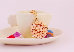 Detailed close-up of pink flower ball keychain with gold accents on a white cup rim