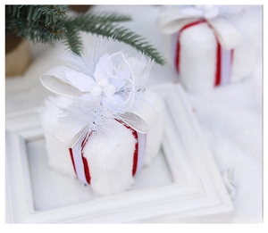 Close-up of white plush Christmas gift box decoration with red ribbon and mesh bow