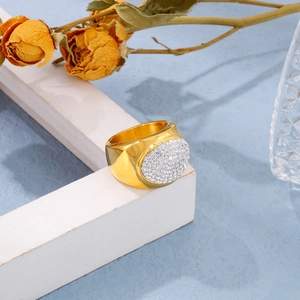 Macro detail of a wide gold ring featuring a sparkling domed surface with white rhinestones