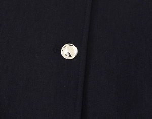 Macro detail of high-quality navy twill fabric and metallic button on blazer sleeve