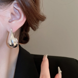 Polished silver teardrop earrings shown on model for size and minimalist style