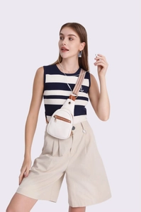 White faux leather chest bag with patterned strap shown on a model against purple background