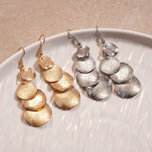Boucles d'oreilles pendantes rondes mates dorées et argentées sur plateau céramique