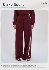 Detail view of burgundy sweatpants with white side stripes featuring relaxed fit and pockets
