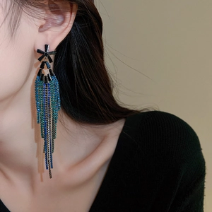 Long tassel floral drop earrings with black, blue, and green crystals on model