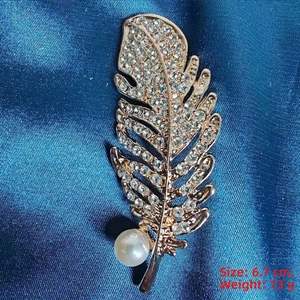 Detailed view of feather brooch featuring rose gold plating, rhinestones, and large pearl