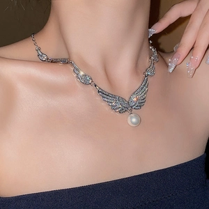 Detail of wing-shaped rhinestone earrings with white pearl pendant on model neck