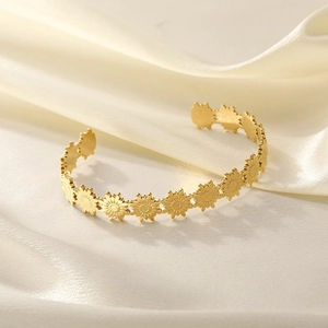 Close-up of golden sunflower open bangle with matte texture on silk fabric background