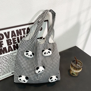 Detail shot of black and white checkered canvas tote bag with 3D panda plush dolls