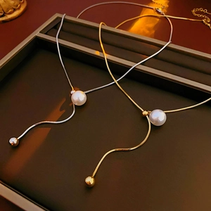 Detailed close-up of gold and silver snake chain necklaces with round pearls