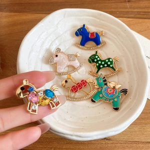 Macro shot of colorful enamel rocking horse brooches with sparkling rhinestone inlay