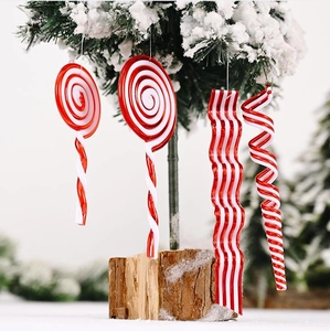 Close-up of red and white acrylic candy ornaments hanging on a snowy Christmas tree