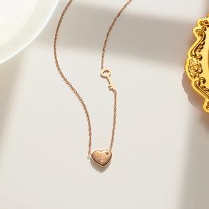 Detail view of rose gold necklace featuring heart and key charms with crystal accents