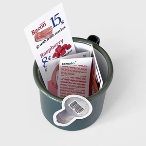 Deep green enamel cup filled with food-themed stickers featuring bacon and raspberry graphics