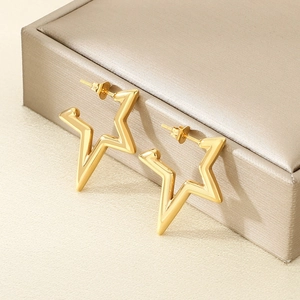 Orecchini a stella d'oro traforati su una scatola di gioielli dal design minimalista