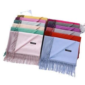 Stacked collection of soft cashmere scarves with tassels in various pastel colors