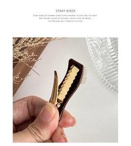 Detail of dark brown acetate hair clip with floral accents and golden metal duckbill structure