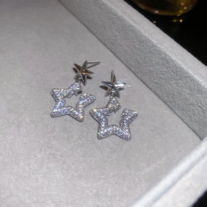 Macro shot of silver star stud earrings with cubic zirconia on gray velvet display