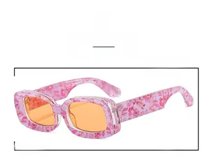 Detail close-up of rectangular pink floral frame sunglasses with vibrant orange lenses