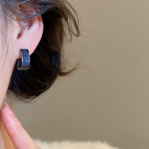 Close-up of model wearing blue zircon hoop earrings with dark metal and pave setting