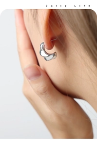 Detailed view of silver twisted C-shaped earrings with polished finish on model
