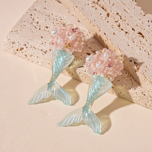 Dettaglio orecchini a sirena con perline rosa e coda in resina blu su base di pietra
