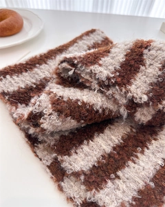 Close-up of the textured brown and beige striped wool knit scarf with soft tassel fringe