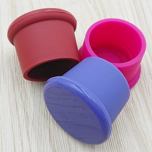 Detailed view of colorful silicone beer caps in red pink and blue on wooden surface