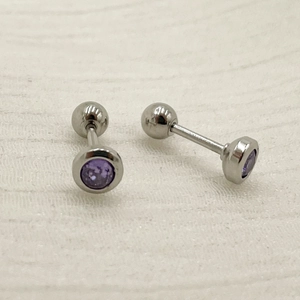 Macro detail of silver titanium steel barbell studs with purple round zircon stones
