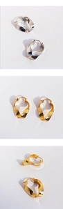 Macro shot showing detail of twisted mobius geometric earrings in gold and silver finish