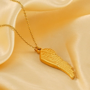 Detailed close-up of golden angel wing pendant with fine texture on silk background
