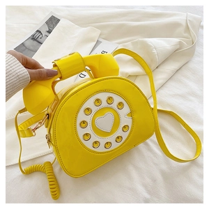 Detailed macro shot of a yellow vintage telephone-shaped bag with heart dial detail