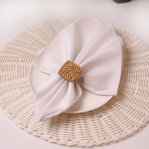 Detail of square brown woven napkin ring on white plate with natural texture