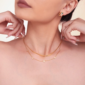 Double-layered gold titanium necklace with star pendant and matching hoop earrings on model
