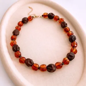 Collier vintage perles marron foncé et ambre présentées sur un plateau élégant