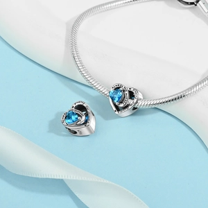 Macro detail of S925 silver heart charm with blue crystal and mother-friend engraving