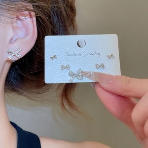 Detailed view of silver bow-shaped rhinestone stud earrings set on display card