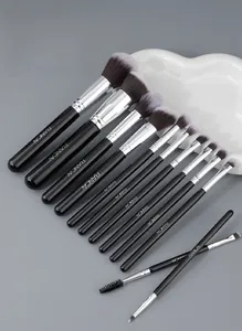 Flat lay of 12 professional black and silver makeup brushes on a grey background