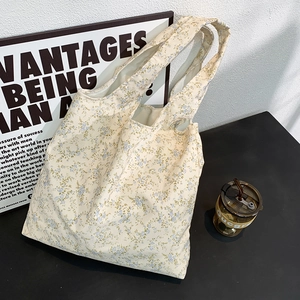 Close-up of small blue floral pattern on beige canvas tote bag with soft fabric texture