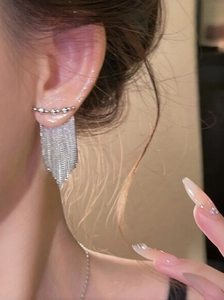 Gros plan de boucles d'oreilles à pompons argentés avec chaînes sur un modèle