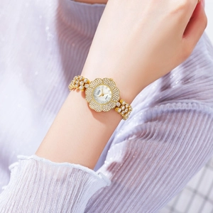 Dettaglio dell'orologio GEDI dorato a forma di fiore con strass sul polso femminile