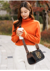 Detail of a vintage Chinese style cylindrical crossbody bag with embossed patterns and GDADA strap